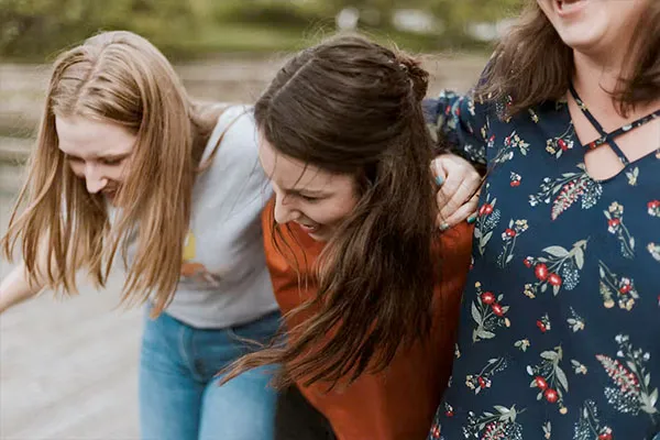 Drei junge Frauen gehen Arm ind Arm