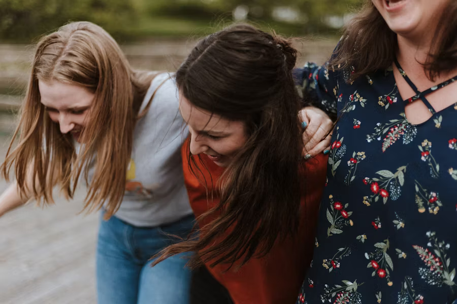 Drei junge Frauen gehen Arm ind Arm